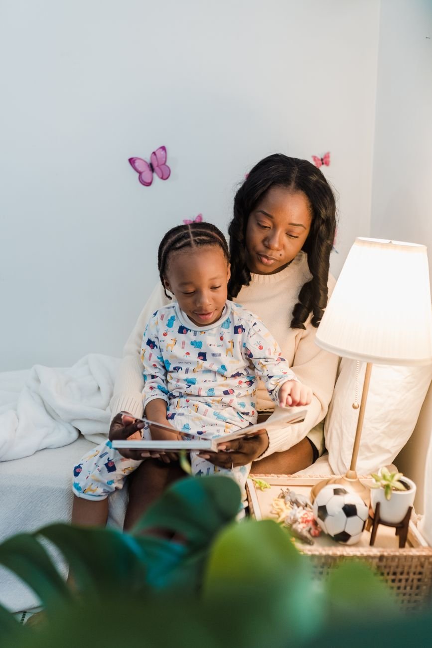 A mother and child reading a book together on a cozy bed with warm lighting and playful decor.